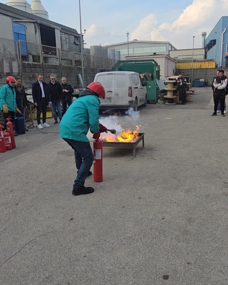 Esercitazione antincendio all'aperto: un partecipante spegne un principio d'incendio con l'estintore